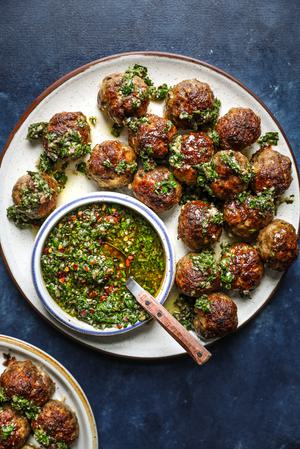 Chimichurri Meatballs on a plate with a bowl of chimichurri sauce
