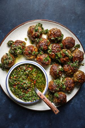Chimichurri Meatballs on a plate with a bowl of chimichurri sauce