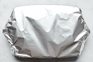 lasagna in a baking dish covered in foil ready to go in the oven