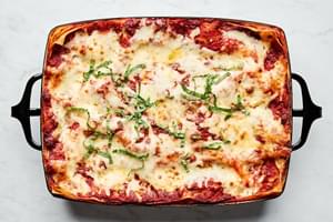 a baking dish of classic lasagna topped with mozzarella, Parmesan and sprinkled with fresh basil