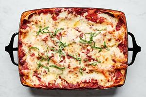 a baking dish of classic lasagna topped with mozzarella, Parmesan and sprinkled with fresh basil