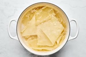 lasagna noodles being boiled in a pot of water