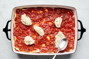 meat sauce, lasagna noodles and ricotta mixture being layered in a baking dish