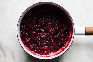 homemade cranberry sauce in a saucepan made with brown sugar, apple cider vinegar, orange zest & juice, vanilla and spices