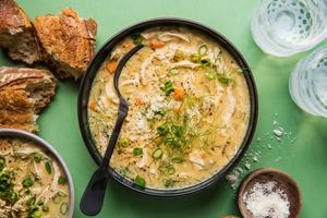 homemade creamy chicken soup in a bowl with a spoon served with crusty bread