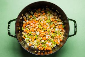 onions, carrots, celery and garlic being cooked in a pot
