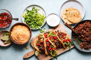 ground taco beef, fried tortillas, shredded lettuce, limes, salsa, Mexican cheese and sour cream