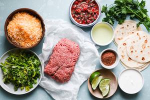 ground beef, grated Mexican cheese, salsa, limes, taco seasoning, tortillas, sour cream and cilantro