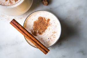 homemade eggnog in glasses with a dusting of nutmeg and a cinnamon stick