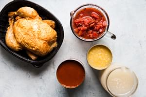 rotisserie chicken, canned tomatoes, red enchilada sauce, chicken stock and corn in bowls on the counter