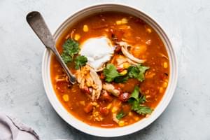 a bowl of 5 ingredient chicken tortilla soup in a bowl topped with sour cream and cilantro