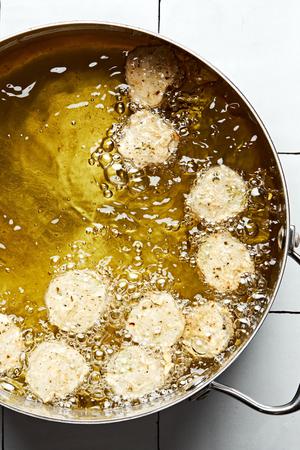 sliced pickles battered in flour, cajun seasoning, parsley, oregano, salt, garlic and onion powders being fried in a pot