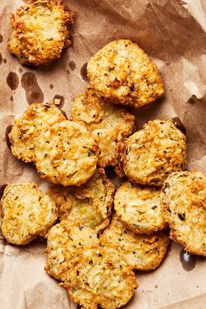 fried pickles seasoned with cajun seasoning, parsley, oregano, salt, garlic and onion powders cooling on parchment paper