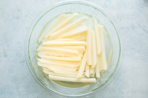 potatoes cut into sticks soaking in a bowl of water