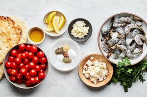 shrimp, tomatoes, spices, feta, spices, parsley and lemon wedges in bowls to make greek shrimp