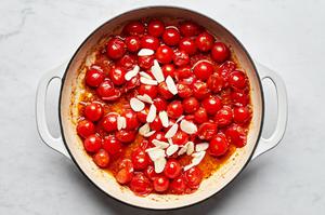 garlic and tomatoes being cooked in a skillet with olive oil