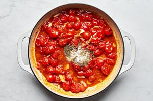 tomatoes, garlic, oregano, thyme, garlic powder, sugar, salt and crushed red pepper flakes being cooked in a skillet