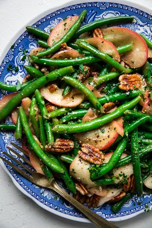 Homemade Green Beans with Apples and Sage Butter on a serving plate with a serving fork
