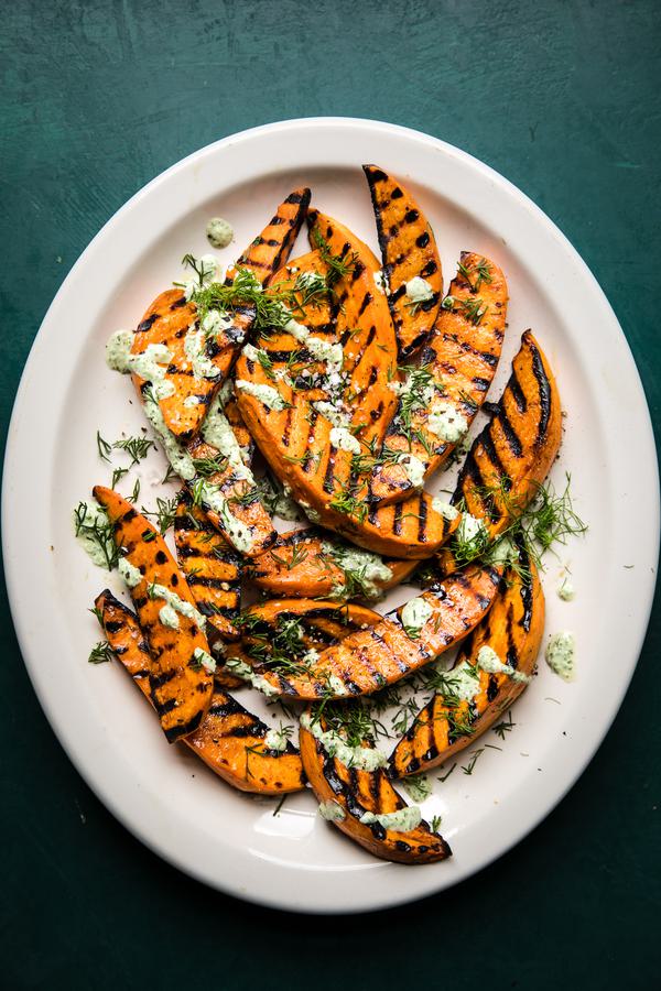 grilled sweet potatoes on a plate with greek yogurt, green onions, fresh dill, garlic, fresh basil and lemon sauce