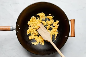 scrambled eggs being cooked in a wok