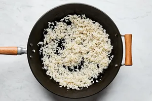 rice being fried in sesame oil and vegetable oil in a wok
