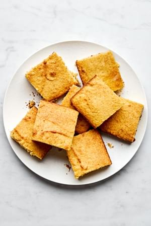 homemade cornbread sliced in to squares stacked on a serving plate