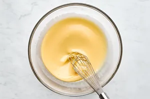 melted butter, sugar, honey, egg, sour cream, and milk being mixed in a bowl