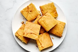 homemade cornbread sliced in to squares stacked on a serving plate