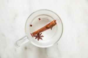 a cinnamon stick, cloves and star anise in a mug with hot water
