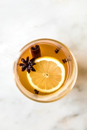 a homemade hot toddy recipe in a mug with cinnamon stick, clove, anise and a lemon slice for garnish