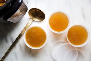 homemade chicken stock recipe being in three containers with a ladle next to an instant pot