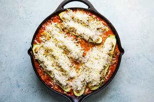 zucchini boats with ground chicken, spices and parmesan cheese in a creamy tomato sauce in a skillet