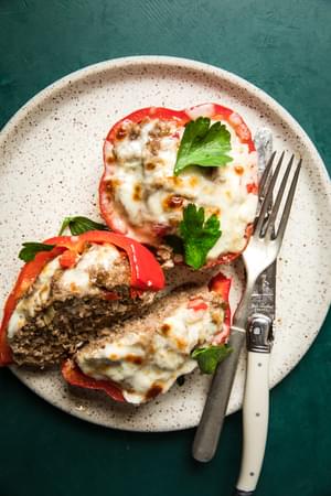 2 meatball stuffed peppers with one sliced in half on a plate with a fork