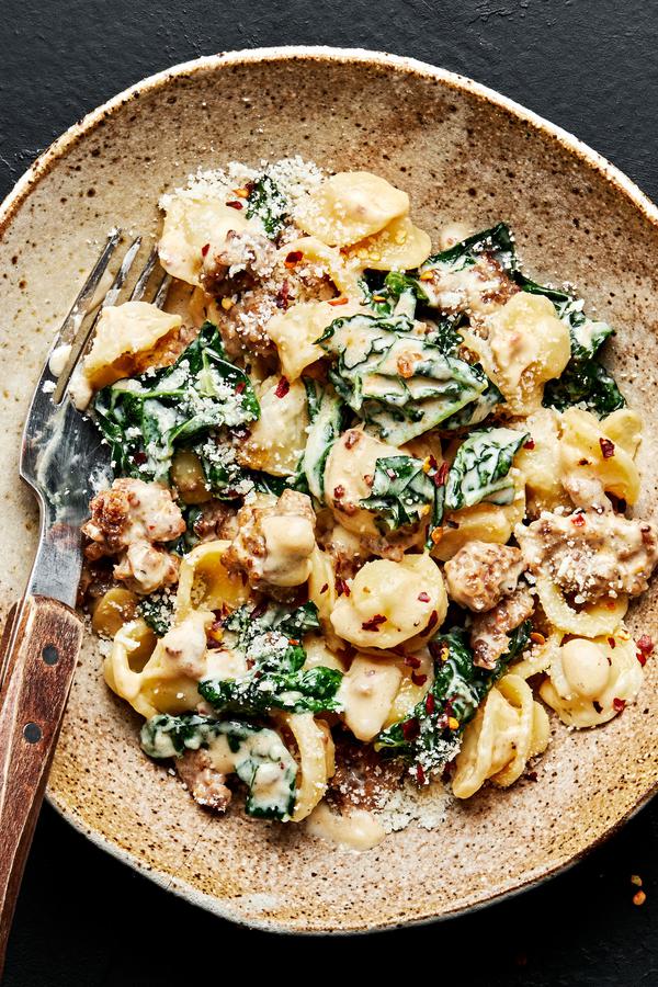 Orecchiette pasta with kale and sausage in a large bowl with a fork.