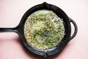 pine nuts, butter and pesto cooking in a skillet