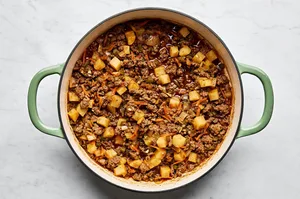 a pan of picadillo made with ground beef, onion, bell pepper, carrots, and spices