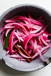 Pickled red onions in a bowl, vibrant and tangy, perfect for adding flavor to tacos, sandwiches, or salads.