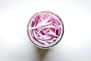 hot sliced red onions added to a jar with brine made of white vinegar, cloves, garlic, sugar, salt, bay leaf & cinnamon stick