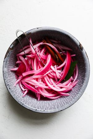 a bowl of pickled red onions in a bowl, vibrant and tangy, perfect for adding flavor to tacos, sandwiches, or salads.
