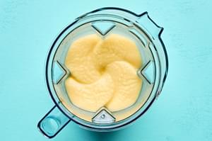 a blender full of piña colada made with pineapple, ice, cream of coconut, pineapple juice, lime juice, light rum & bitters