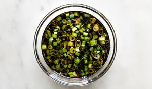 A bowl of poke marinade made from low-sodium soy sauce, green onions, toasted sesame oil, rice vinegar & pickled ginger juice