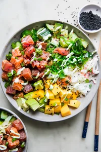 A poke bowl featuring a base of seasoned rice, topped with tuna salmon, mango, cucumber salad, avocado & citrus wasabi sauce
