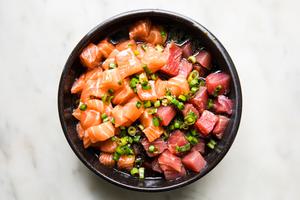 sushi grade tuna and salmon marinating in a bowl of soy sauce, green onion, sesame oil, rice vinegar and pickled ginger juice