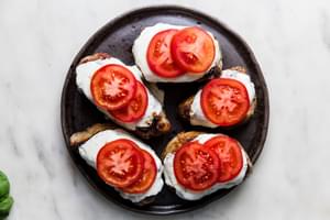 grilled pork chops topped with mozzarella and tomato slices on a platter