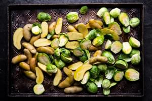 fingerling potatoes and brussels sprouts halved on a baking sheet with olive oil and salt