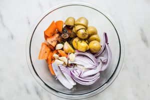 chopped potatoes, carrots, apples and red onion in a glass bowl on the counter