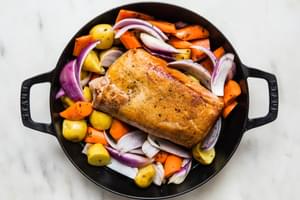 pork loin roast and roasted apples, carrots and potatoes in a dutch oven