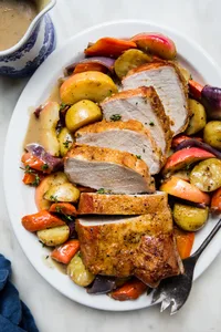Pork Loin Roast with roasted apples and root veggies and finished with a cider gravy on a serving platter
