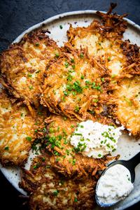 homemade potato pancakes on a plate topped with a dollop of sour cream