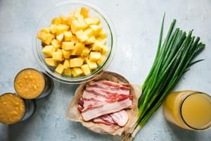 diced yellow potatoes, green onions, bacon, chicken stock and creamed corn in bowls on the counter